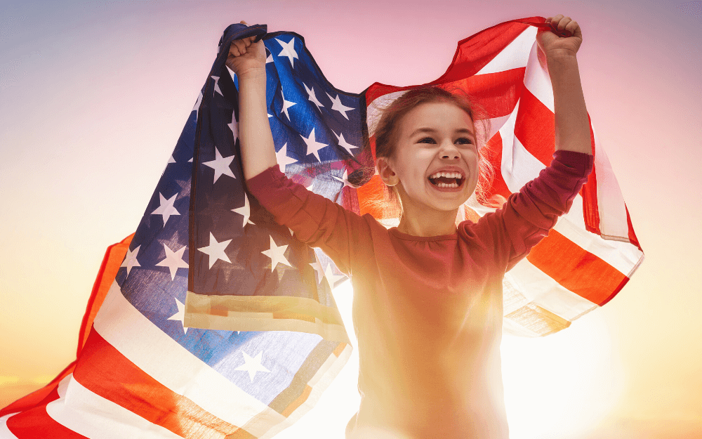 4th-of-july-math-activities-that-are-sure-to-bring-fireworks-5 Young girl holding and American flag at dusk.